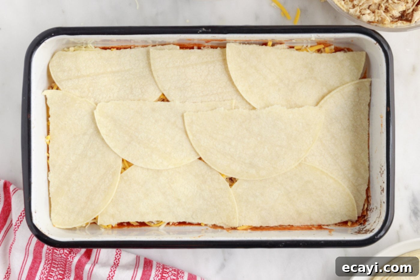 Cheesy Chicken Enchilada Bake 8 Another layer of corn tortillas covering the chicken and cheese, ready for more sauce.