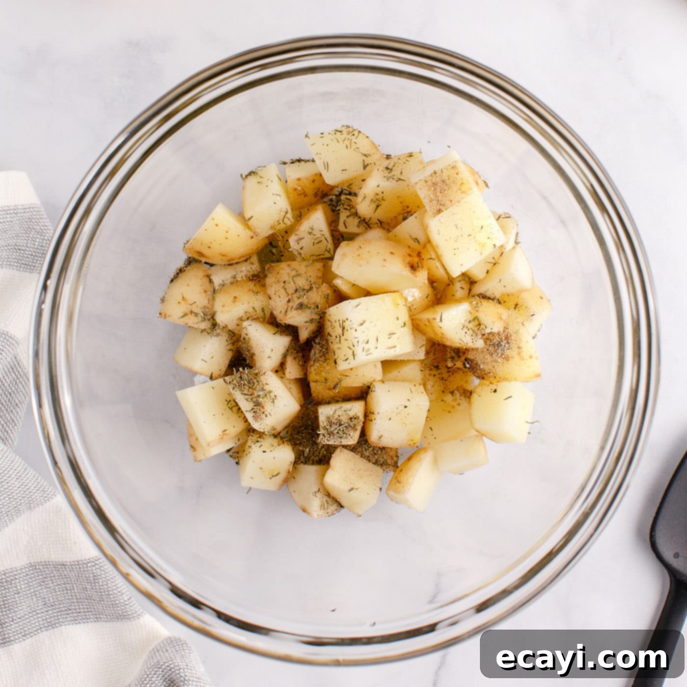 Crispy Corned Beef Hash 5 Cubed white potatoes mixed with oil and seasonings in a bowl, ready for roasting