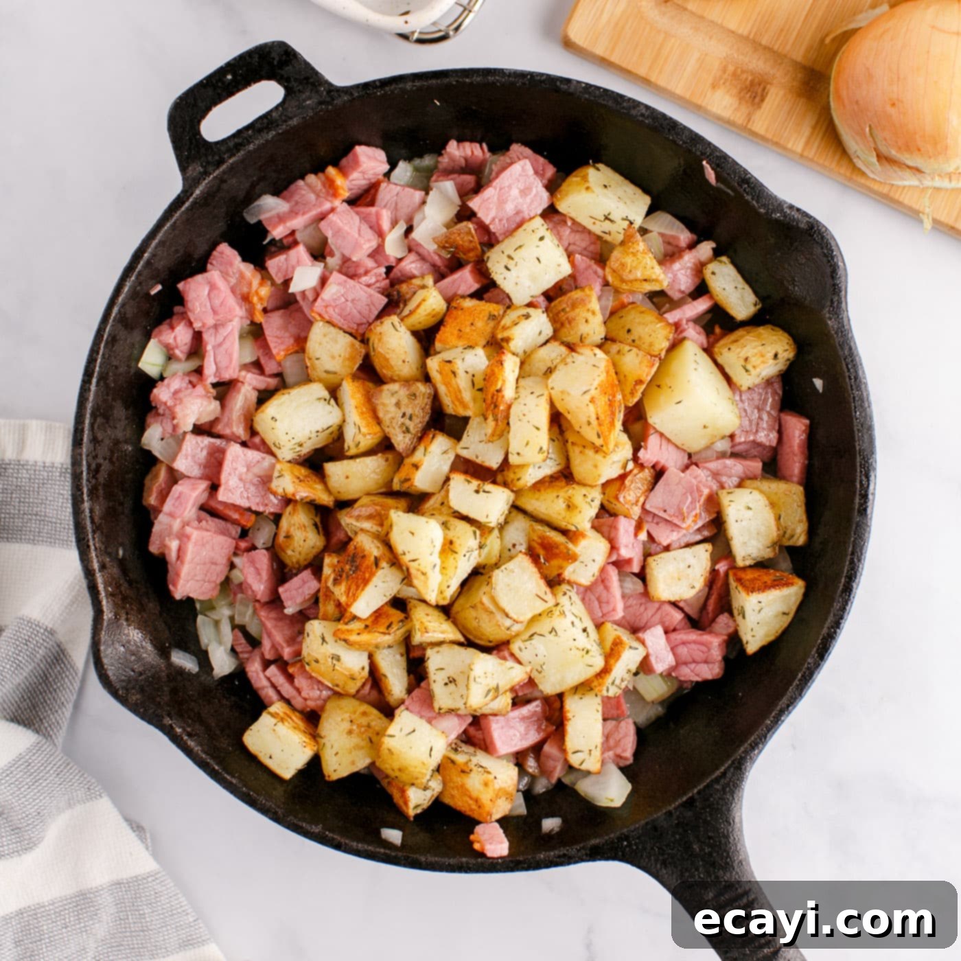 Crispy Corned Beef Hash 9 All ingredients – potatoes, corned beef, and onions – combined and cooking in a cast iron skillet