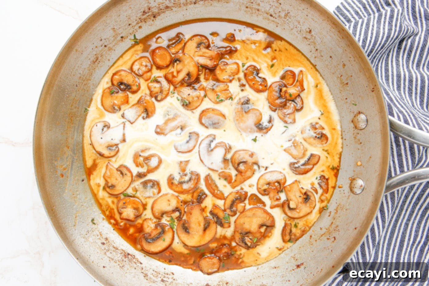 Savory Chicken Marsala 9 Heavy cream and Marsala wine broth being added to sautéed mushrooms in a skillet