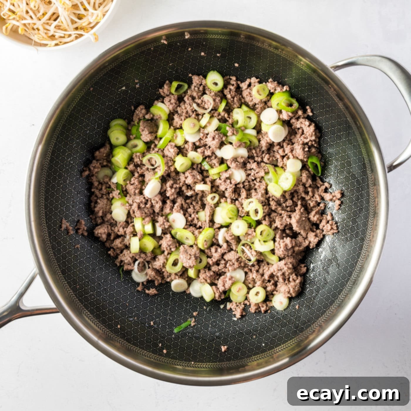 Egg Roll Stir-Fry Bowl 5 Ground beef, spring onions, and garlic cooking in a large skillet