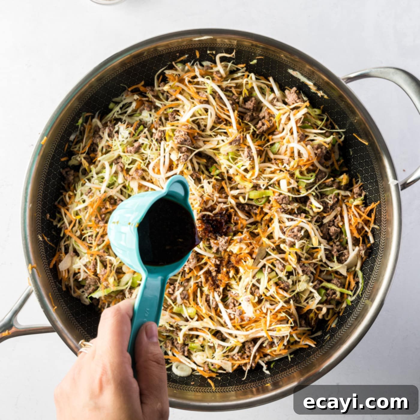 Egg Roll Stir-Fry Bowl 8 Adding the prepared savory sauce to the egg roll in a bowl ingredients in the skillet