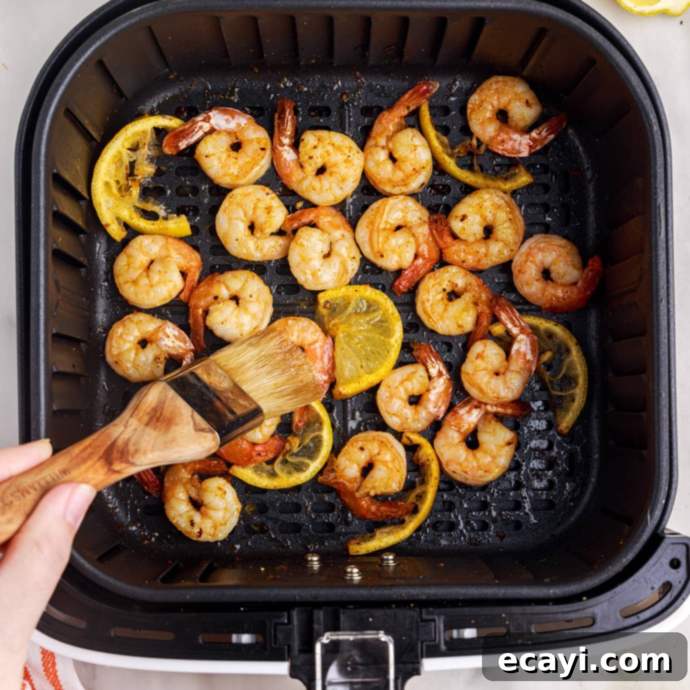 Crispy Air Fryer Shrimp 11 brushing melted butter onto shrimp in air fryer basket
