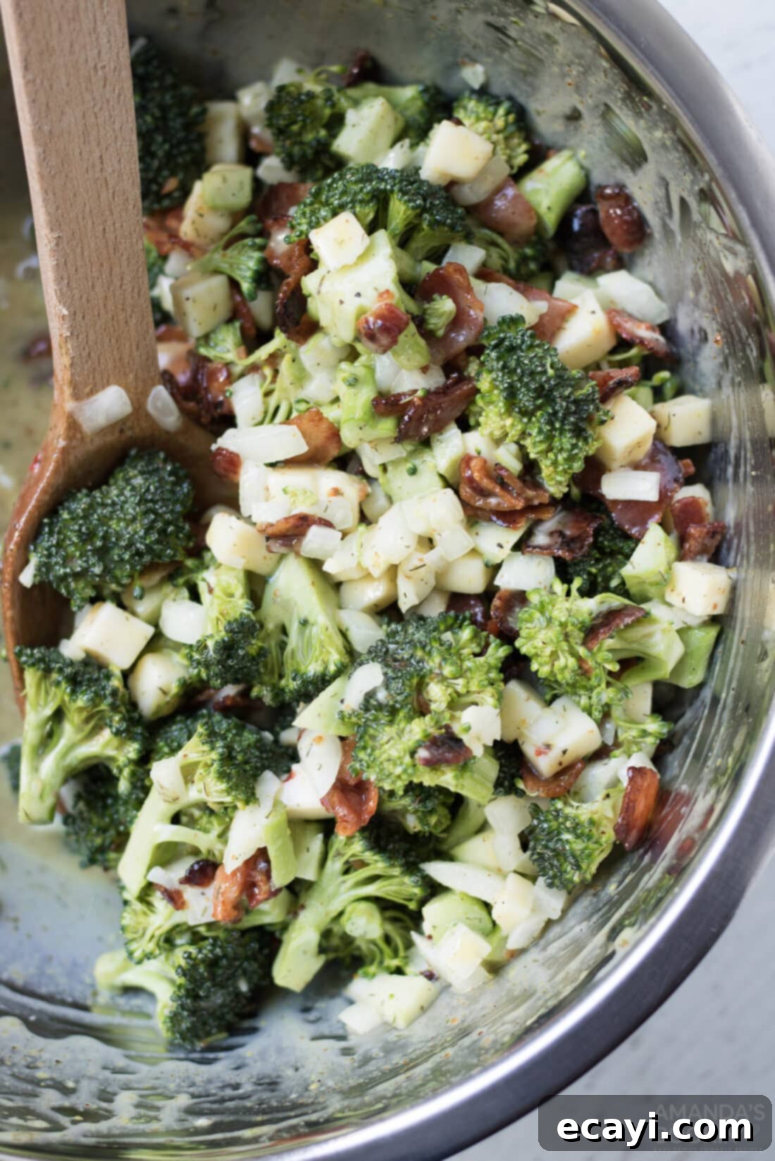 This broccoli salad is a fresh mixture of broccoli, bacon, cheese, and onion. Bring this staple dish to your next potluck or family gathering! #appetizers #potluck #saladrecipes #broccolisalad #broccoli #bacon #sidedishes #summerrecipes  bowl of broccoli salad