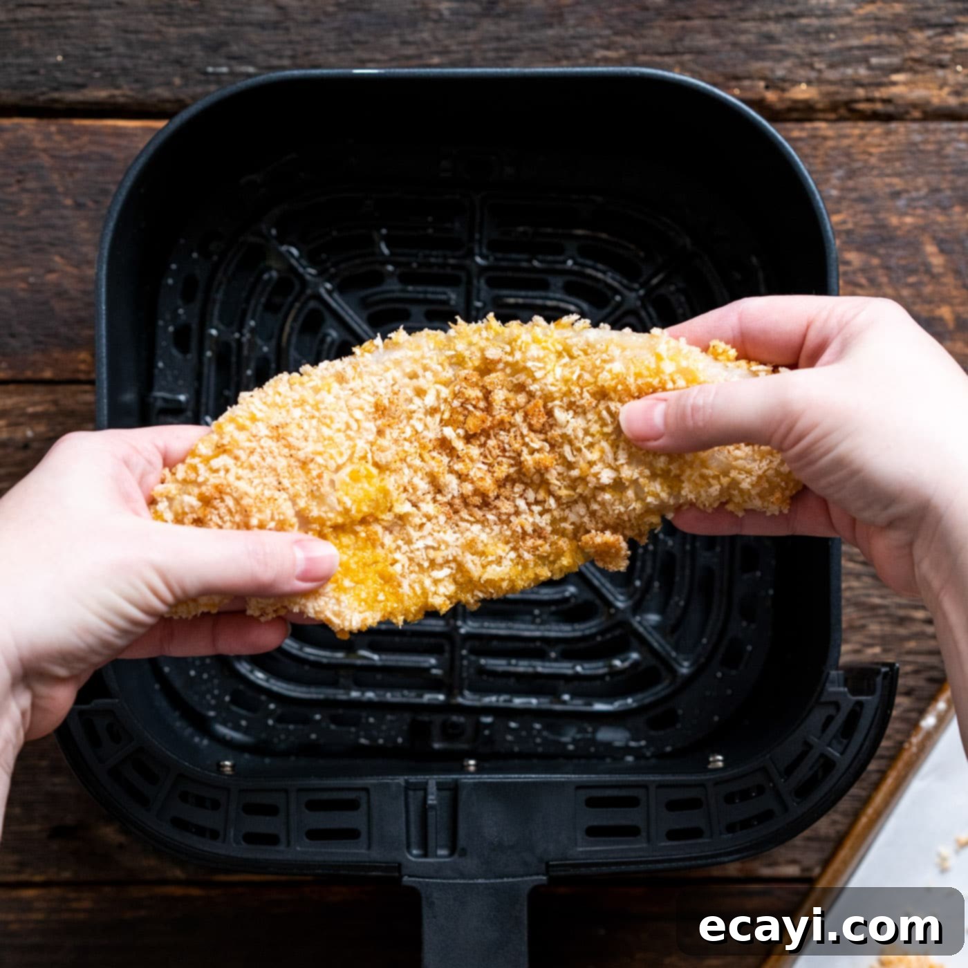 Effortless Air Fryer Fish Perfection 11 breaded fish above air fryer basket