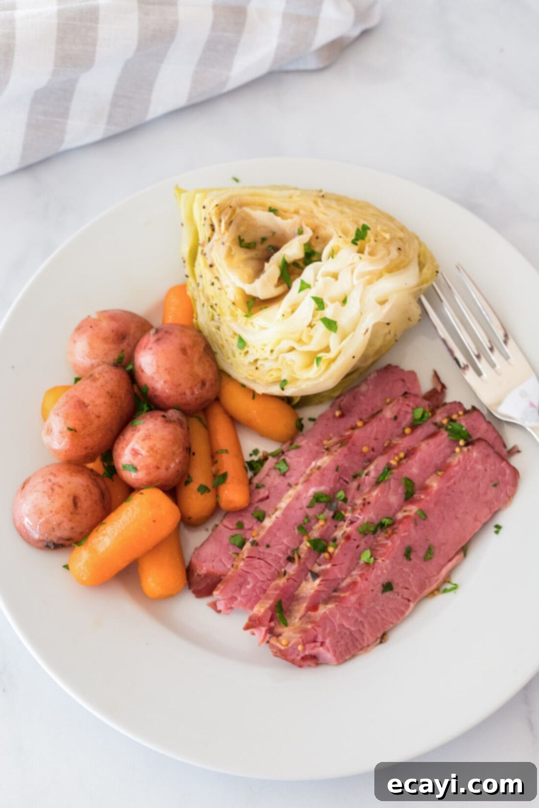 Tender Instant Pot Corned Beef 2 Instant Pot Corned Beef on a plate with cabbage, carrots and potatoes, garnished with fresh parsley.