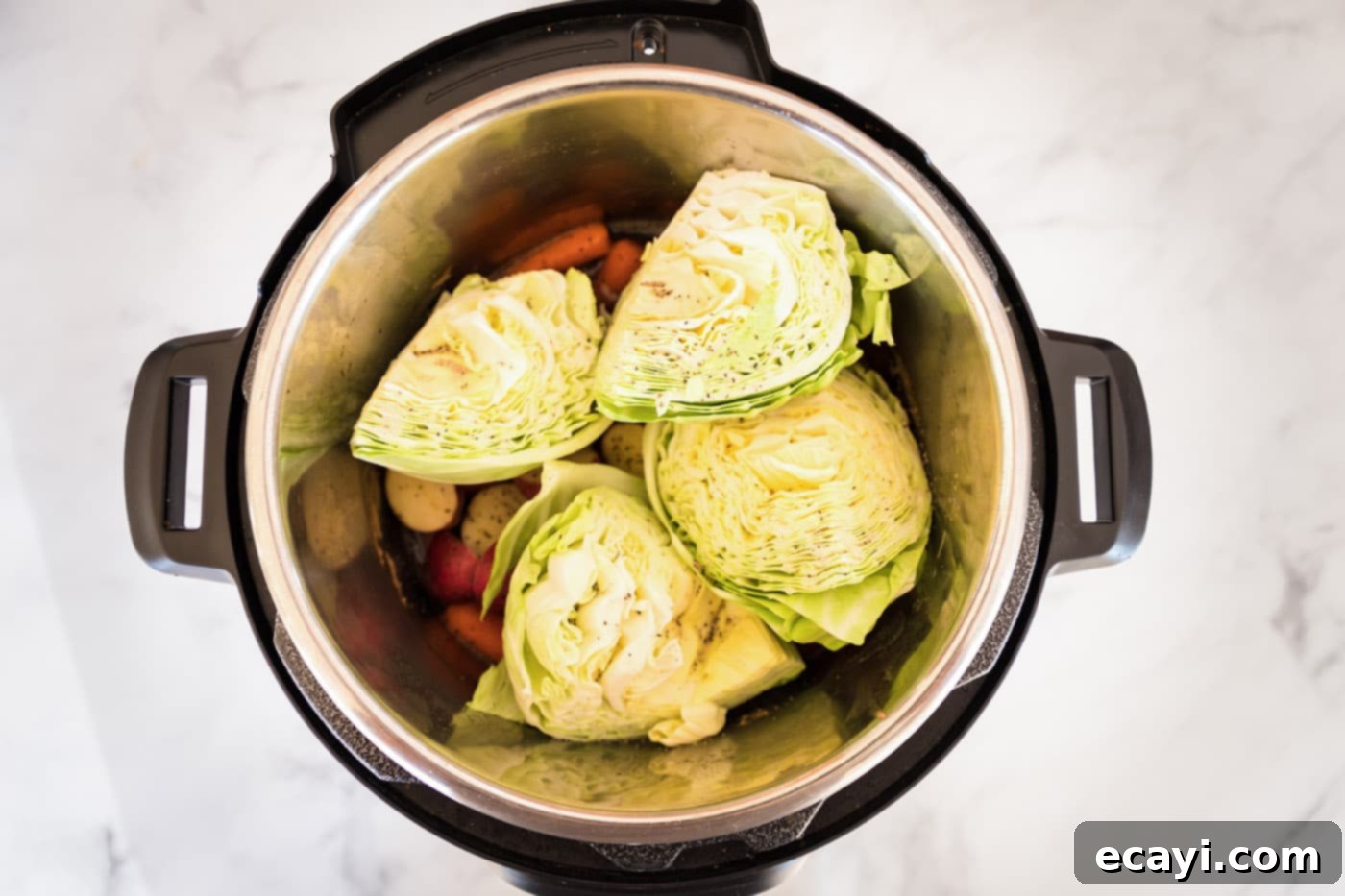 Tender Instant Pot Corned Beef 11 Cabbage wedges placed over baby potatoes and carrots in the Instant Pot for the final cooking stage.