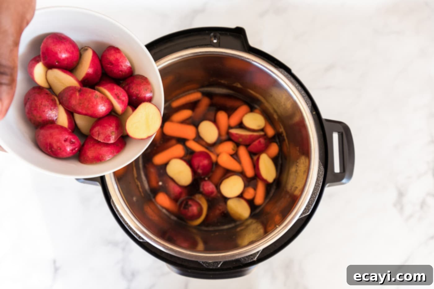 Tender Instant Pot Corned Beef 10 Baby potatoes and carrots added to the Instant Pot with liquid, ready for cooking.