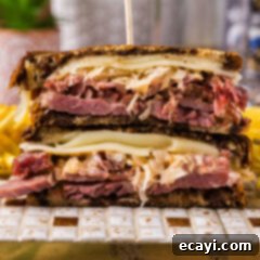 Classic Reuben Sandwich 11 Close up photo of a Reuben Sandwich cut in half stacked on top of each other, showcasing the layers of meat, cheese, and sauerkraut.