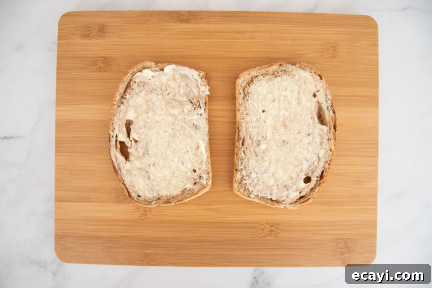 Classic Reuben Sandwich 5 Buttered rye bread slices laid out on a cutting board, ready for the next step of making a Reuben sandwich.