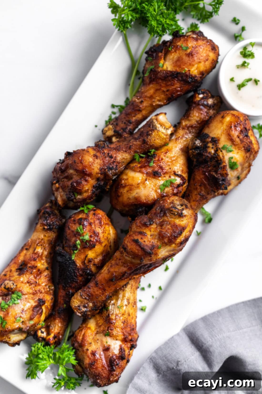 Golden Crispy Air Fryer Drumsticks 2 Air Fryer Chicken Drumsticks arranged on a platter with fresh herbs