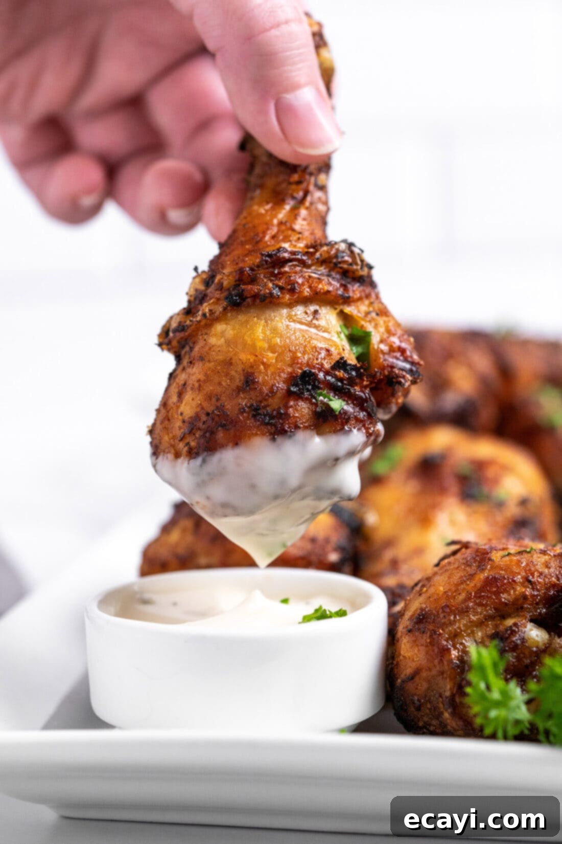 Golden Crispy Air Fryer Drumsticks 8 A crispy air fryer chicken drumstick being dipped into a creamy ranch sauce