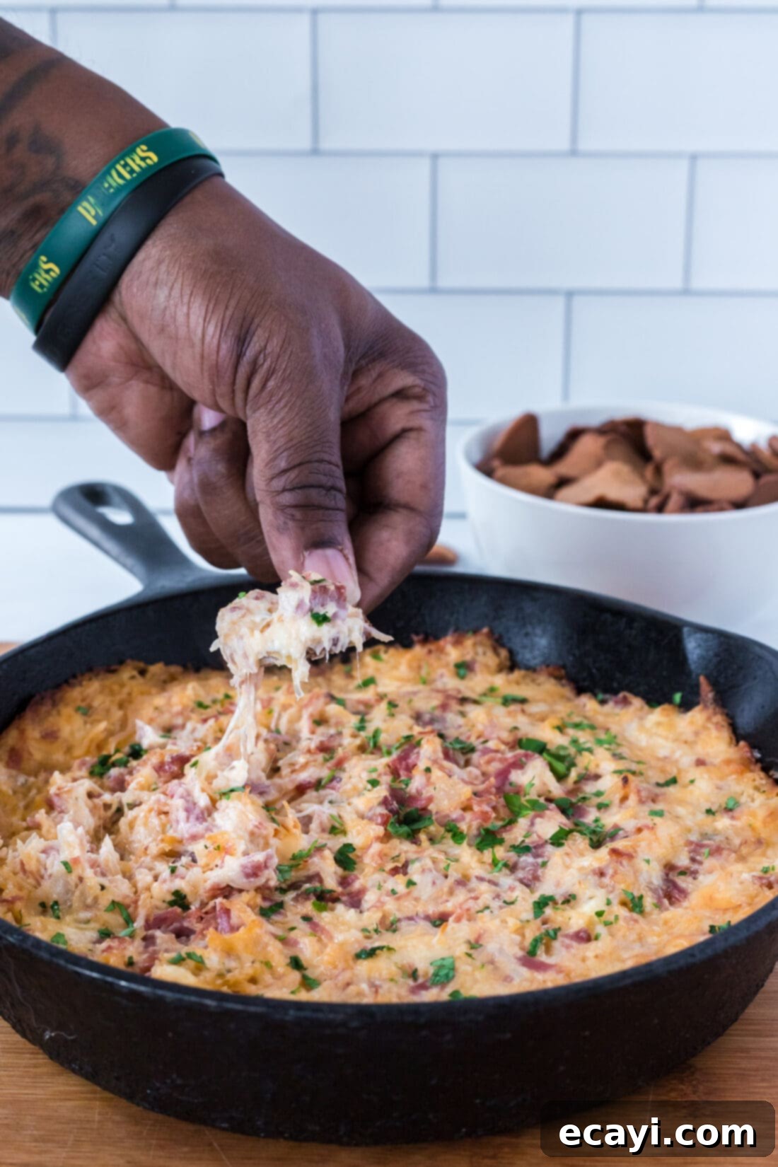 Decadent Reuben Dip 3 dipping a chip into warm, cheesy Reuben Dip