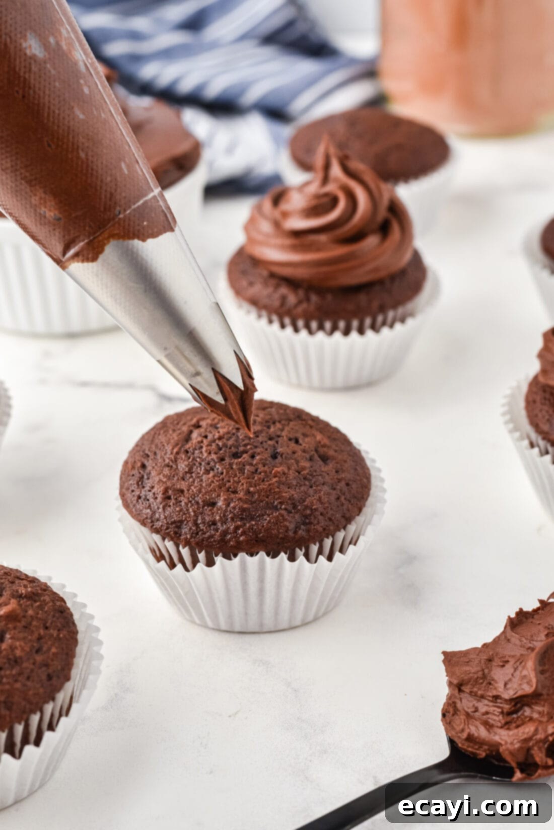 Velvet Chocolate Fudge Bliss 3 Piping Silky Chocolate Fudge Frosting onto a freshly baked cupcake