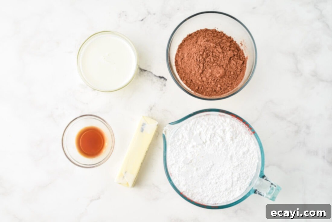 Velvet Chocolate Fudge Bliss 4 All 5 ingredients laid out for making the chocolate fudge frosting: butter, cocoa powder, powdered sugar, heavy cream, and vanilla extract.