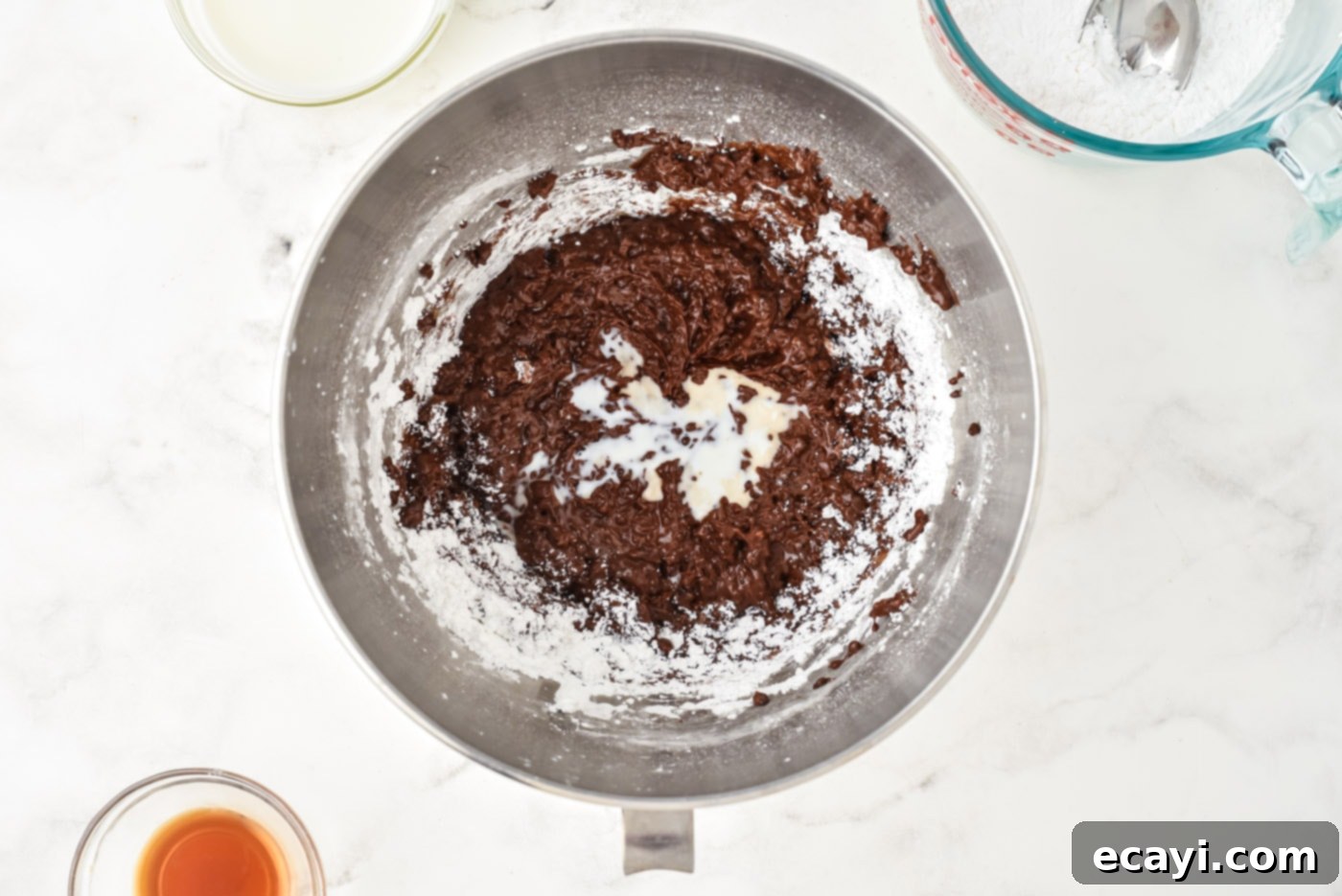 Velvet Chocolate Fudge Bliss 6 Powdered sugar and heavy cream being added to the rich chocolate base in a stand mixer bowl
