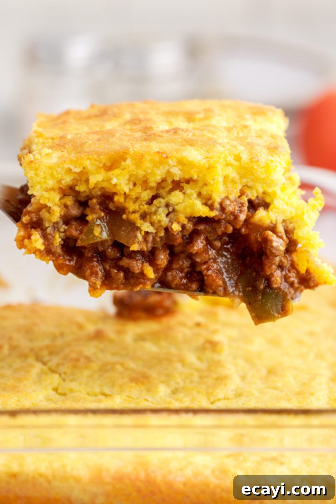 Hearty Sloppy Joe Cornbread Bake 2 lifting spatula of Sloppy Joe Cornbread Casserole, showcasing the fluffy cornbread topping and savory meat layer