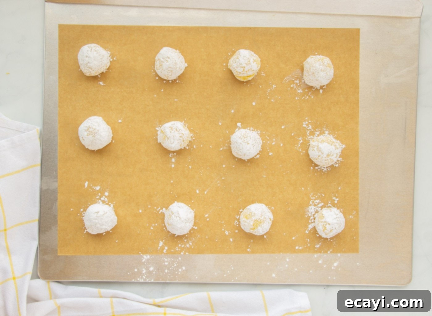 Bright Lemon Cake Mix Cookies 12 Lemon crinkle cookies coated in powdered sugar arranged on a baking sheet