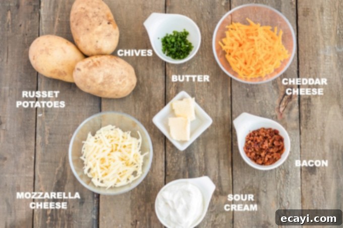 Cheesy Bacon & Chive Twice Baked Potatoes All the fresh ingredients for twice baked potatoes laid out on a wooden cutting board: potatoes, sour cream, butter, bacon, chives, and shredded cheeses.