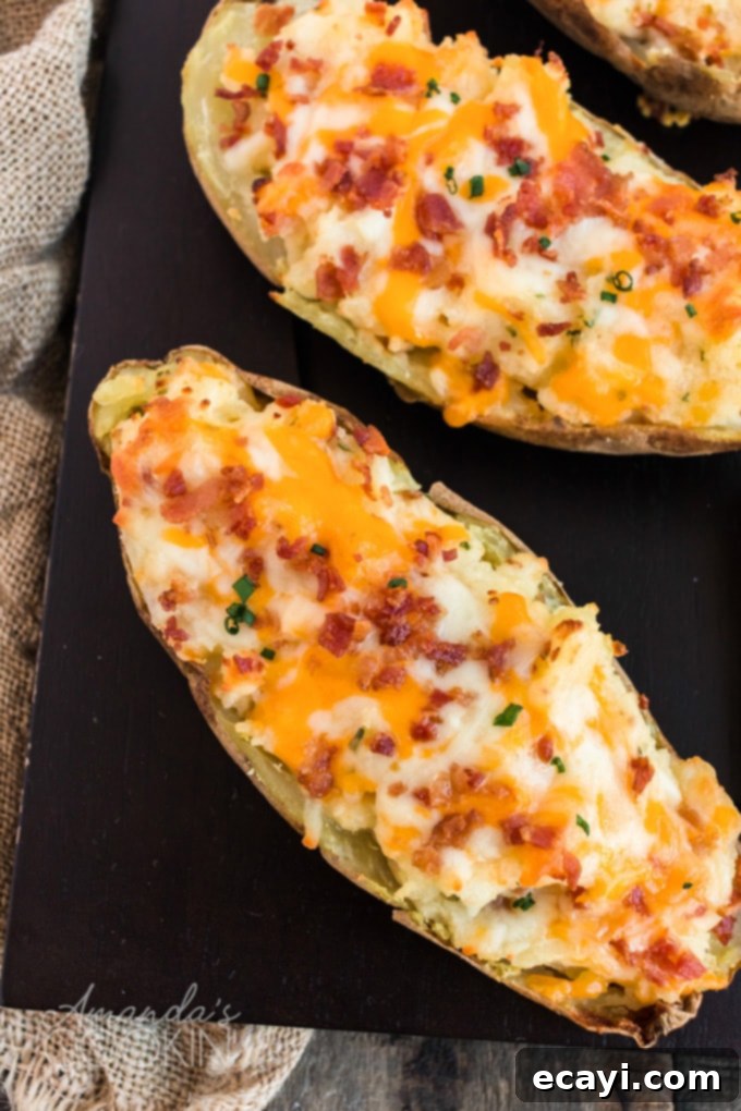 These twice baked potatoes were surprisingly easy to make! Packed with cheese, bacon, and chives, these stuffed potatoes are a favorite in this house. An overhead shot of a baking sheet filled with perfectly golden and bubbly twice baked potatoes, garnished with fresh chives, ready to serve.