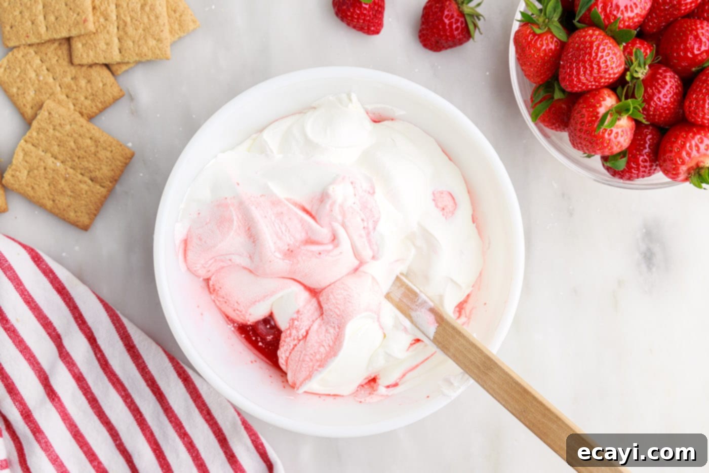 Strawberry Tiered Trifle 10 wooden spoon folding whipped topping into strawberry mixture