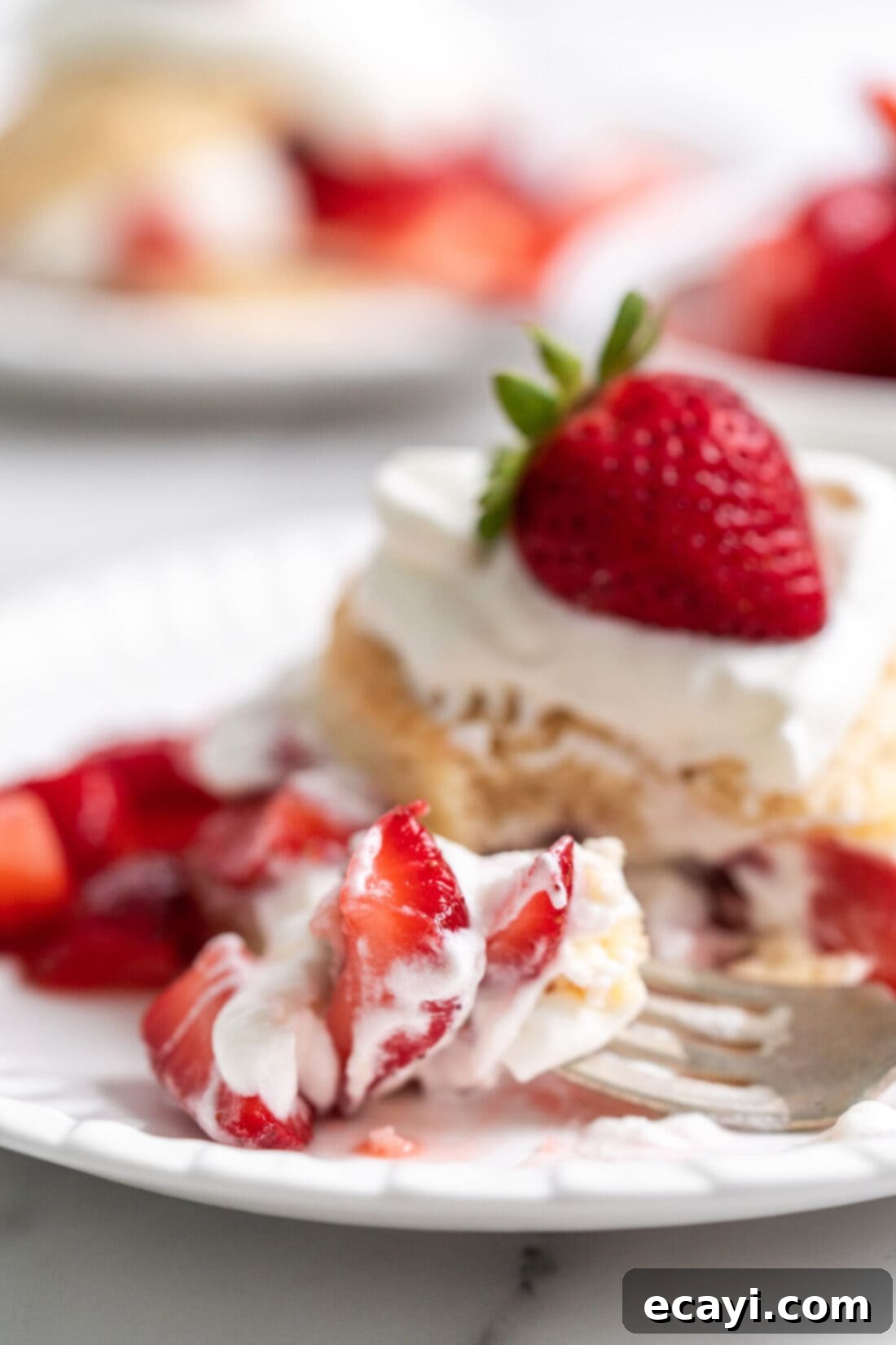 Garden Fresh Strawberry Shortcake 3 Close-up of a Strawberry Shortcake with a fork, showing layers of biscuit, strawberries, and whipped cream