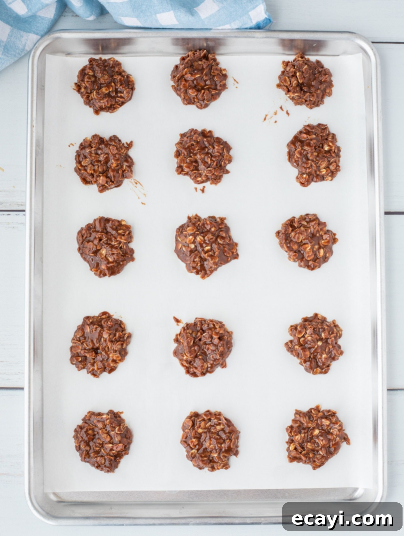 Quick Chocolate No-Bake Delights 11 Rows of scooped chocolate no-bake cookies on parchment paper-lined baking sheets