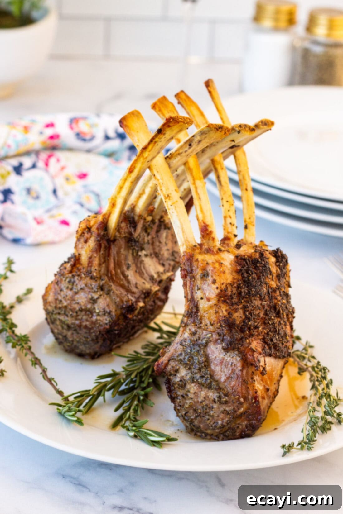 The Butcher's Crown 2 A perfectly cooked rack of lamb, golden brown and garnished with fresh herbs, resting on a white plate.