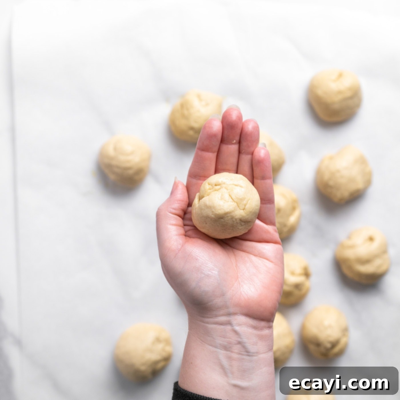 Pillowy Garlic Swirls 11 Individual portions of dough shaped into smooth, small balls, held gently in a baker's hand, ready for rolling into ropes.