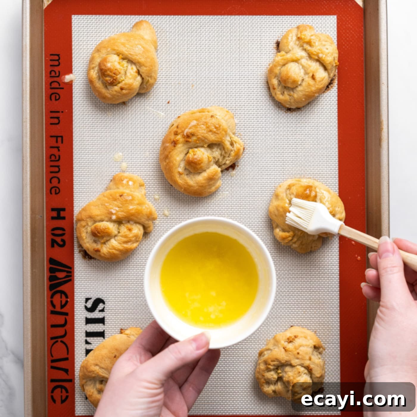 Pillowy Garlic Swirls 15 A baking brush applying an extra layer of melted garlic butter to freshly baked, golden-brown garlic knots, enhancing their flavor and shine.