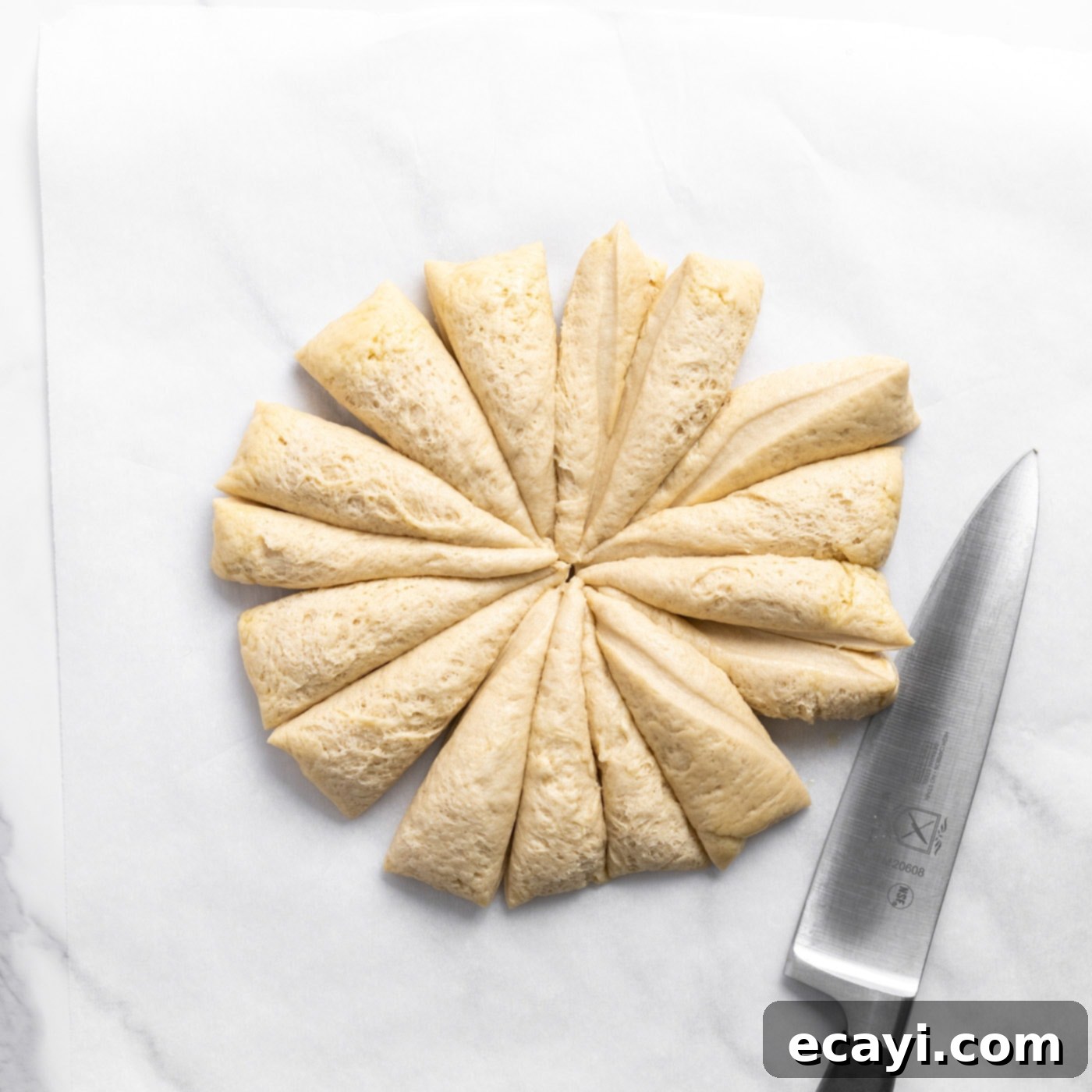 Pillowy Garlic Swirls 10 Bread dough being sectioned into individual portions using a dough cutter on a clean wooden surface, preparing for knot shaping.