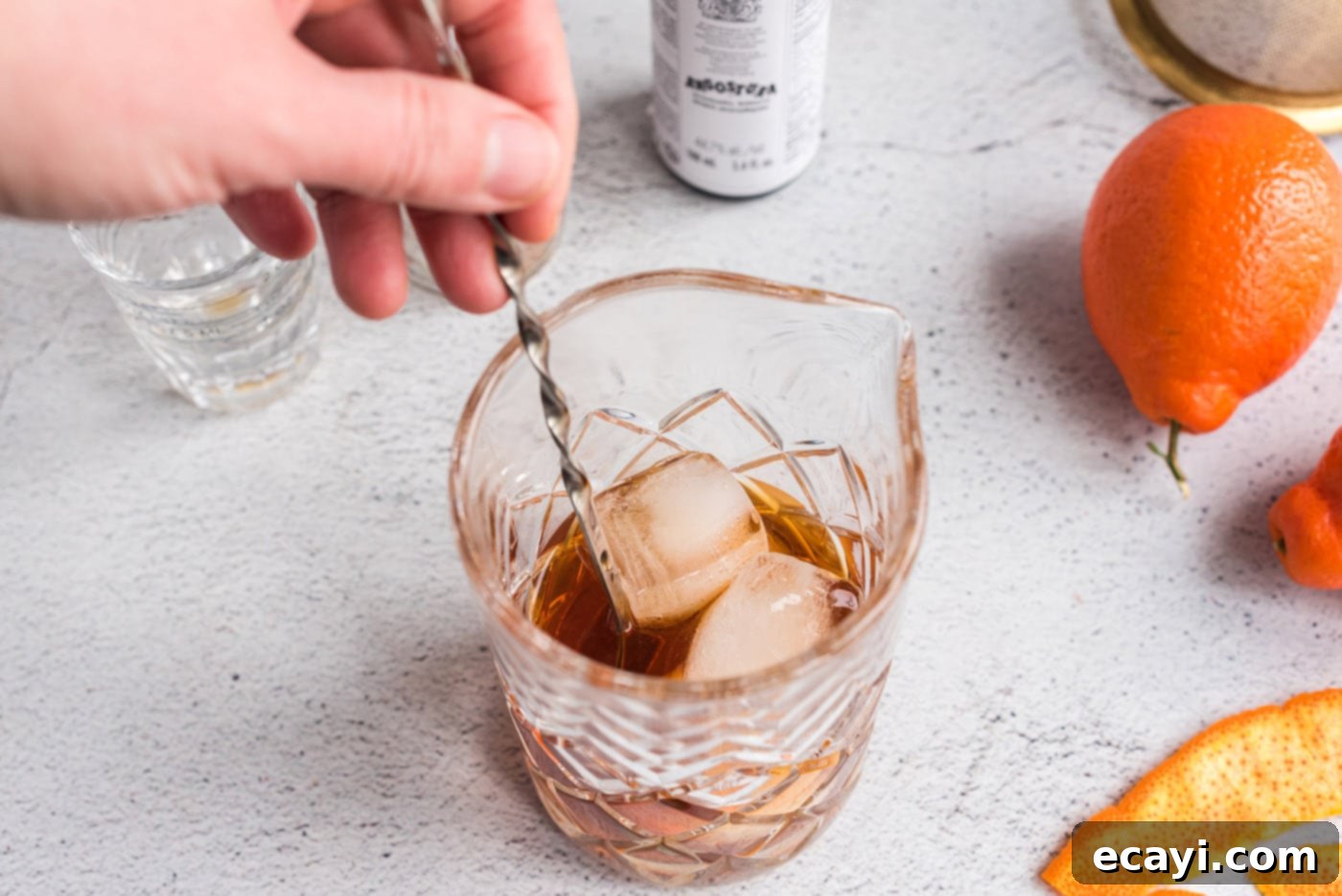 Manhattan's Signature Spirit 7 Stirring the Manhattan cocktail ingredients with ice in a mixing glass using a bar spoon.