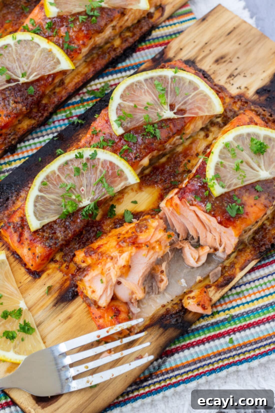Smoky Cedar Plank Salmon 2 Glistening cedar plank salmon filet with sweet and smoky glaze, garnished with lemon and herbs