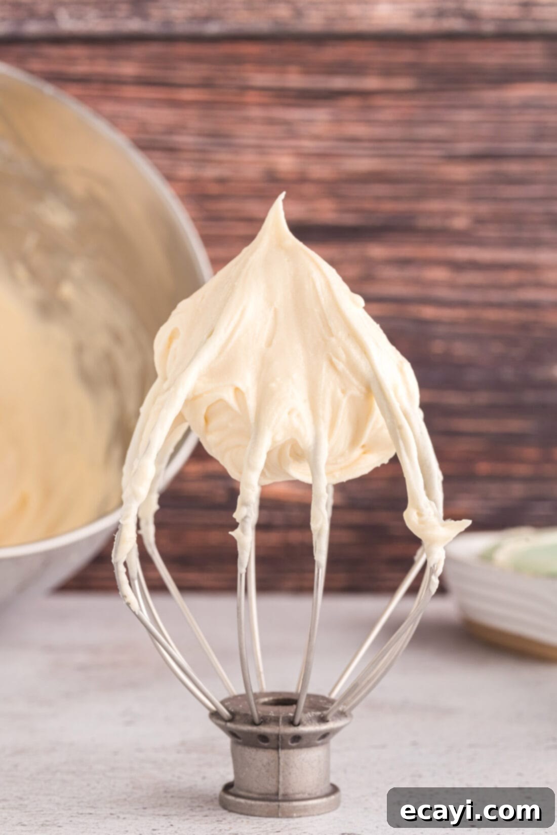 Luscious Cream Cheese Frosting 3 Close-up of freshly made cream cheese frosting on a whisk, showcasing its creamy texture.