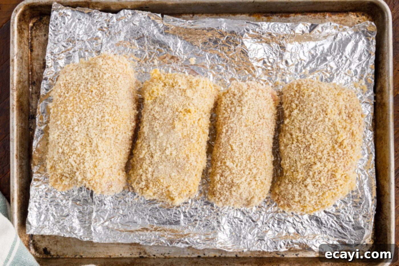 Gourmet Stuffed Chicken Rolls 12 Breaded chicken cordon bleu rolls arranged on a foil-lined baking sheet, ready for the oven