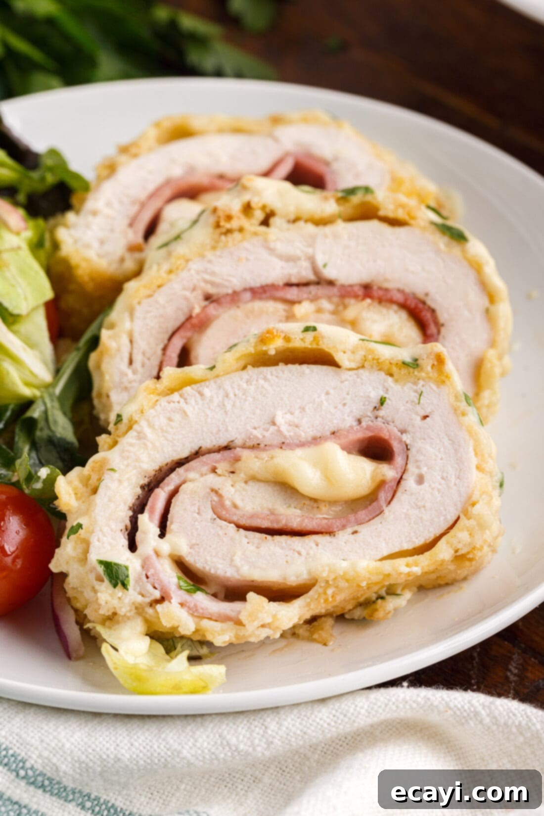 Gourmet Stuffed Chicken Rolls 15 Two slices of baked chicken cordon bleu on a platter, revealing the ham and Swiss cheese filling