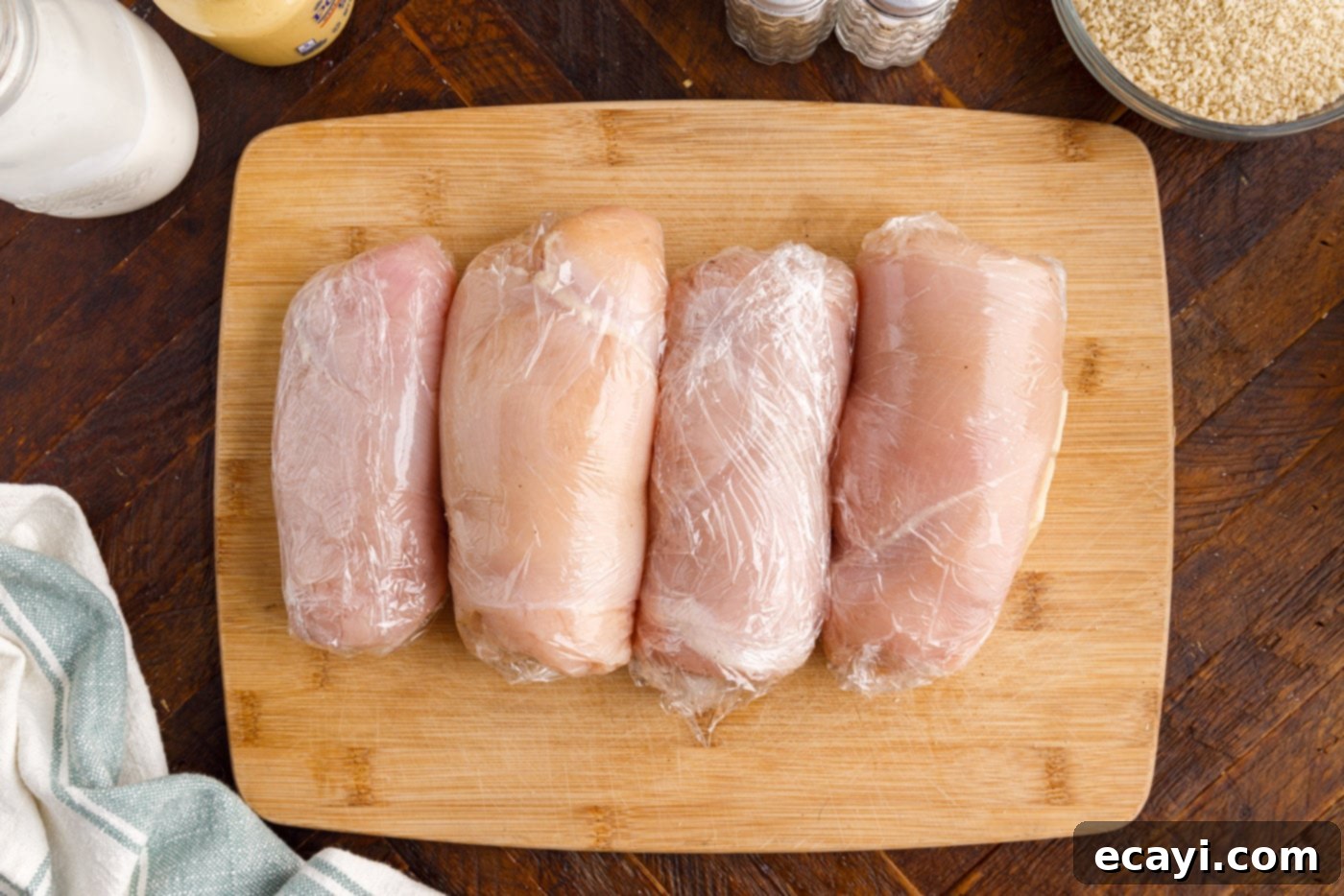 Gourmet Stuffed Chicken Rolls 8 Tightly rolled chicken breast with ham and cheese, secured with plastic wrap, resting on a cutting board