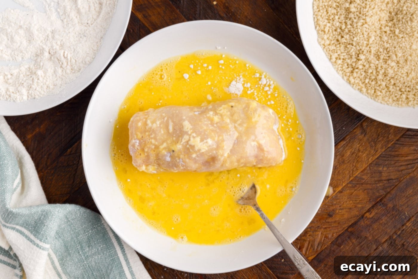 Gourmet Stuffed Chicken Rolls 10 Coating a rolled chicken breast in whisked egg wash, preparing it for breading