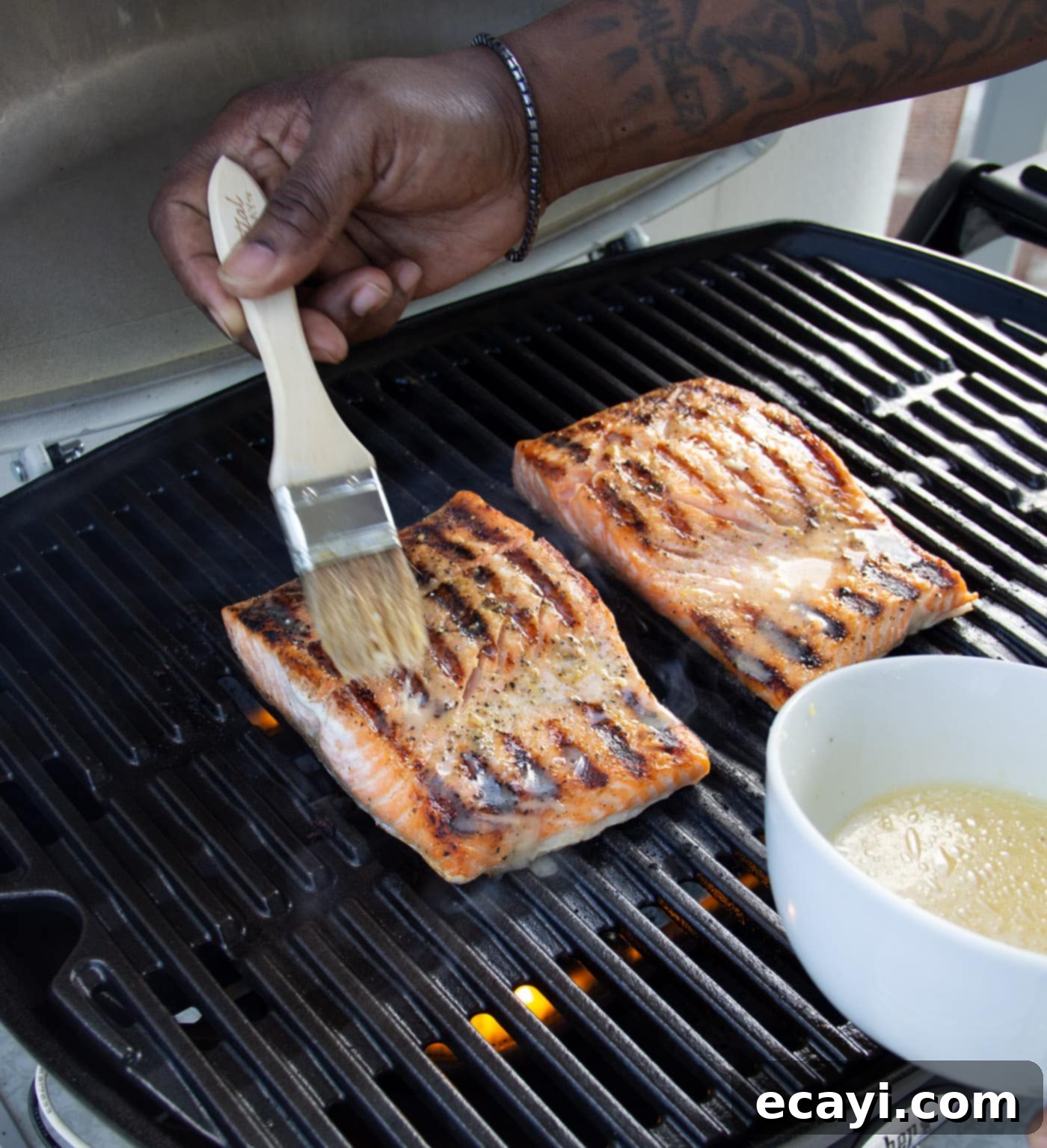 Lemony Salmon 6 Basting grilled salmon fillets with lemon garlic marinade on the grill, enhancing their flavor and creating a beautiful glaze.