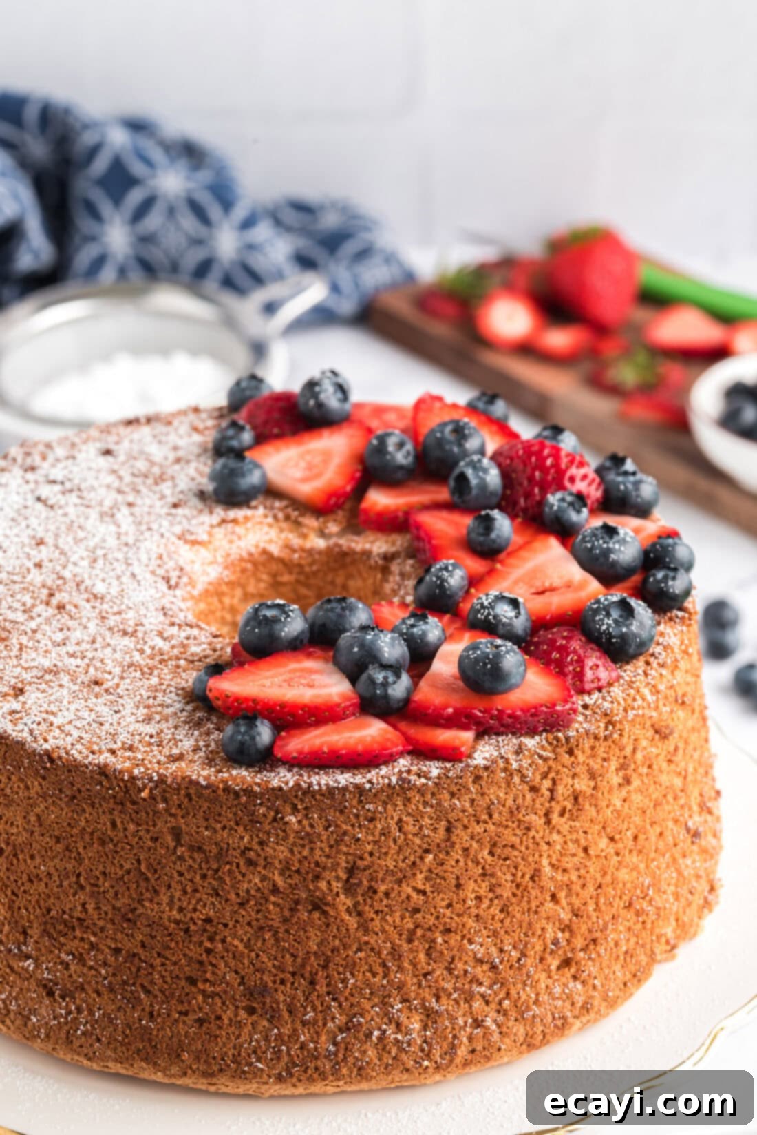 Heavenly Homemade Angel Food Cake 14 Angel Food Cake topped with powdered sugar and mixed berries, ready to be served
