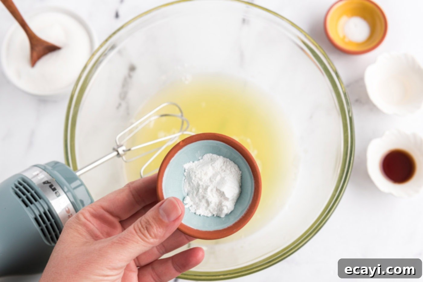 Heavenly Homemade Angel Food Cake 7 Adding cream of tartar to egg whites in a mixing bowl with an electric mixer