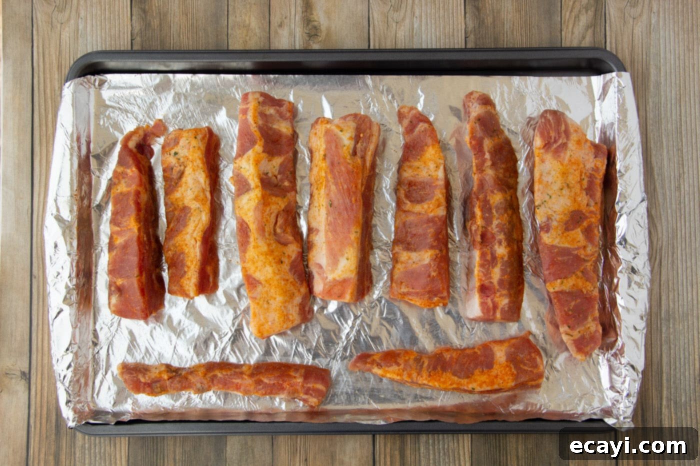 Smoked Rib Ends 5 Seasoned rib tips arranged on a foil-lined baking sheet, ready for the oven to begin the slow cooking process.