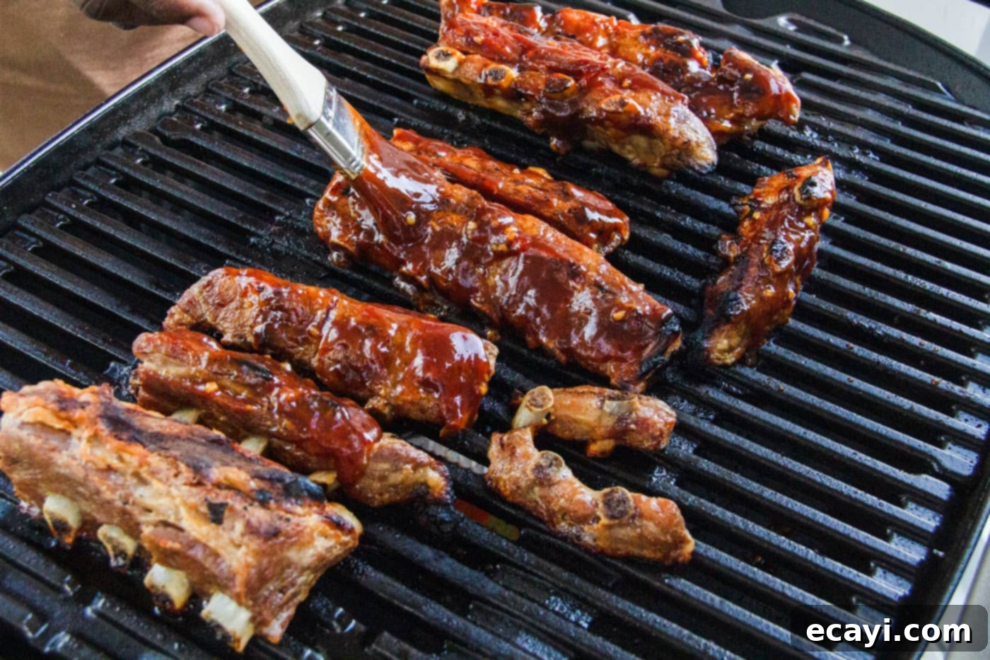 Smoked Rib Ends 6 A basting brush applying a rich, tangy barbecue sauce to rib tips on a hot grill, creating a delicious glaze.