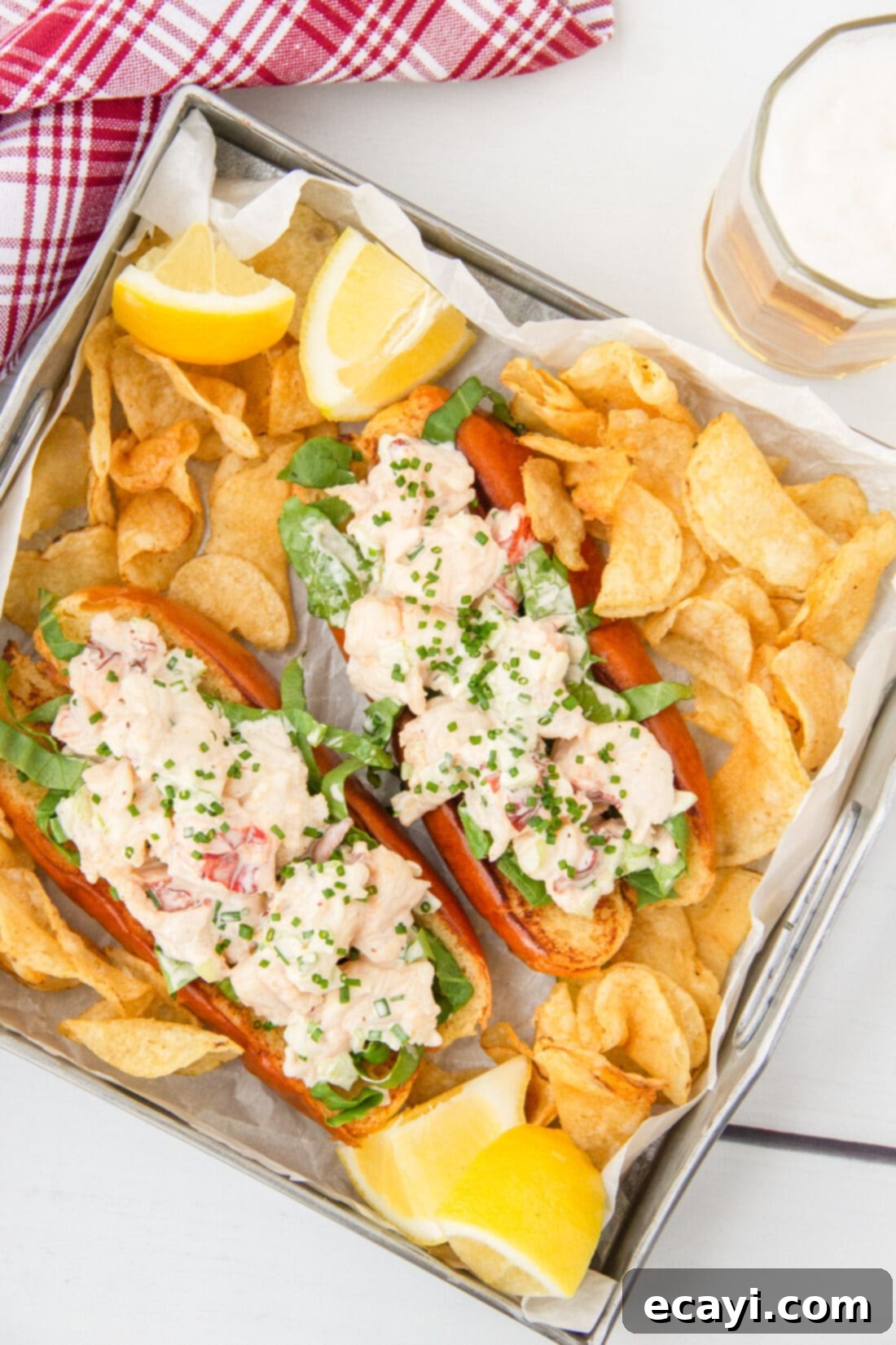 Signature Lobster Roll 2 Classic New England Lobster Roll served with a side of crispy potato chips on a rustic wooden board.