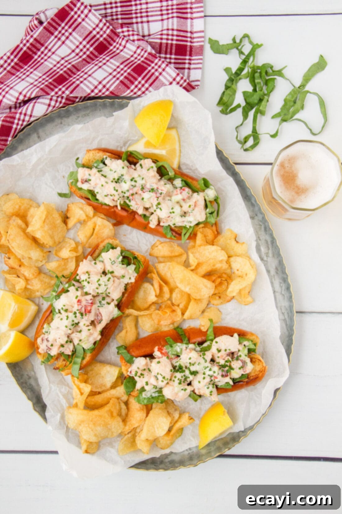 Signature Lobster Roll 10 Three perfectly assembled lobster rolls generously filled with creamy lobster salad, arranged on a large platter with a side of crispy potato chips, ready for a delicious meal.