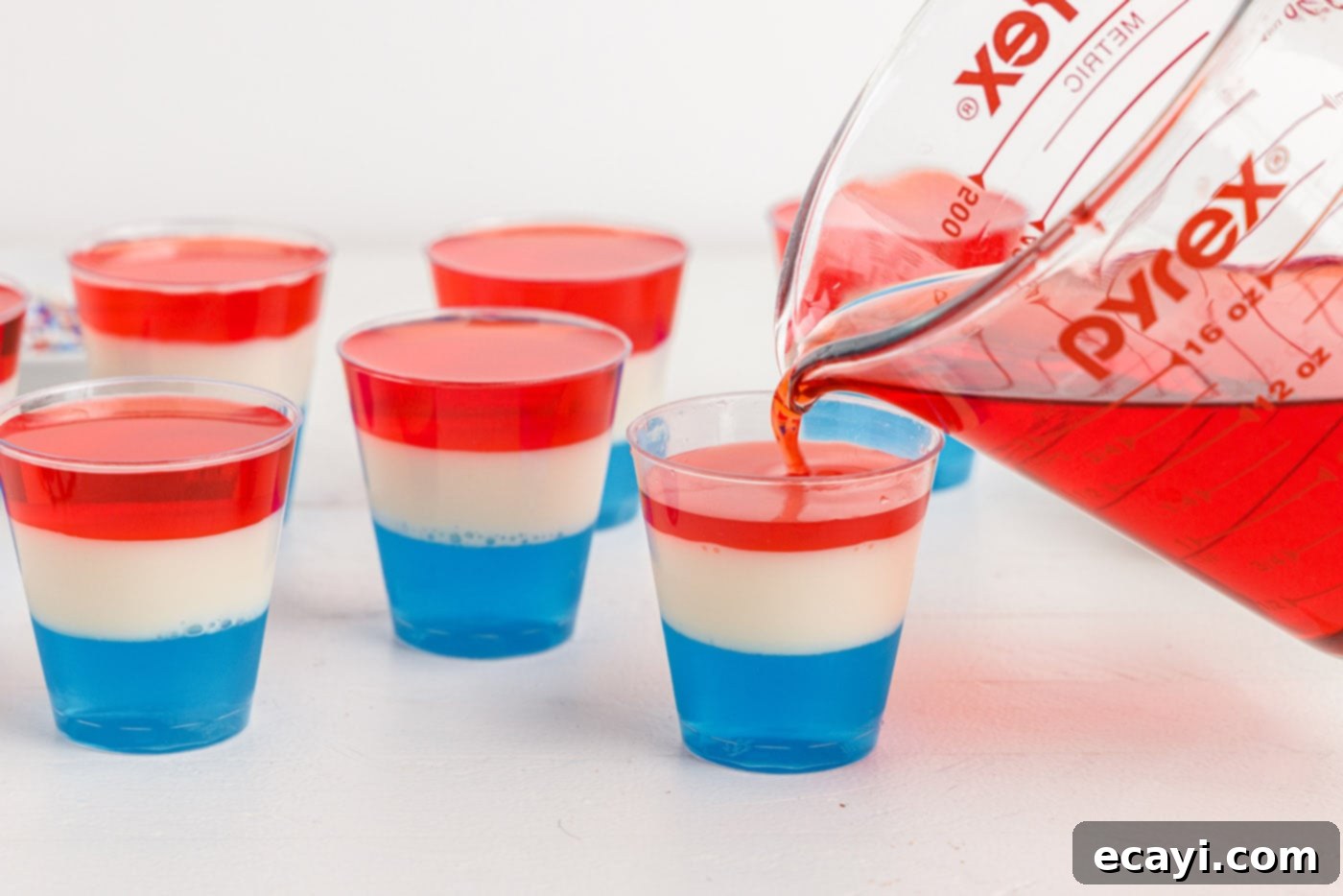 Star-Spangled Gelatin Shots 11 pouring red jello on top of blue and white
