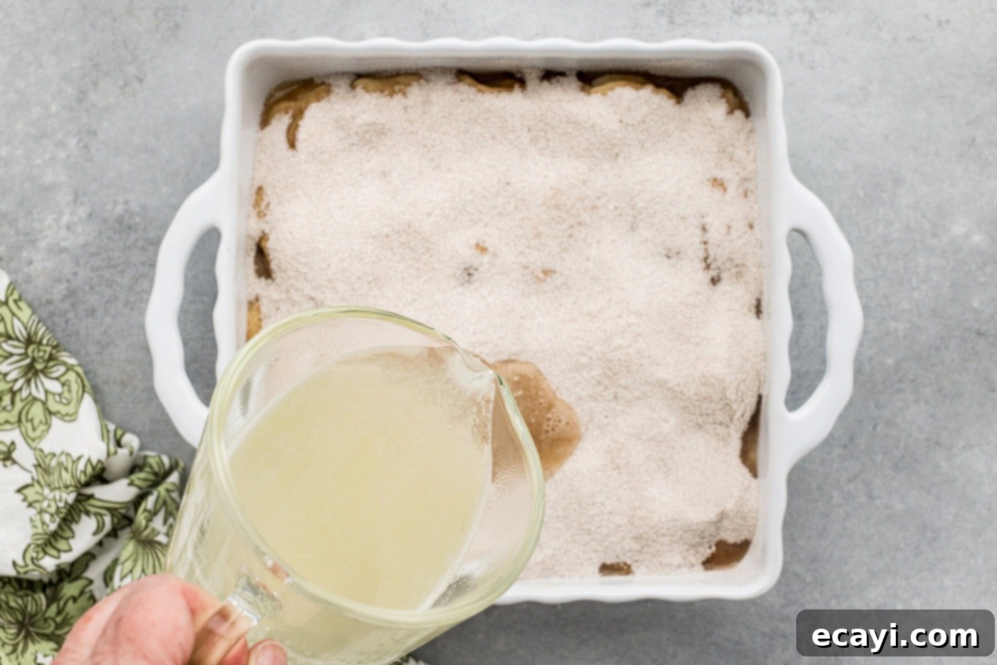 Golden Pear Peach Cobbler 11 pouring warmed fruit juices over unbaked cobbler in a baking dish