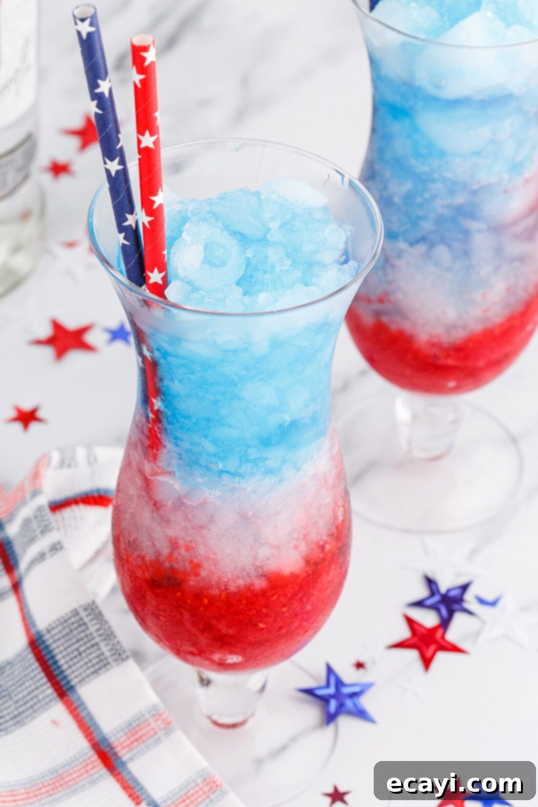 Red White & Boozy Freeze 11 A pair of Patriotic Vodka Lemonade Slushies, garnished with fresh fruit and patriotic flag picks, set against a festive background.