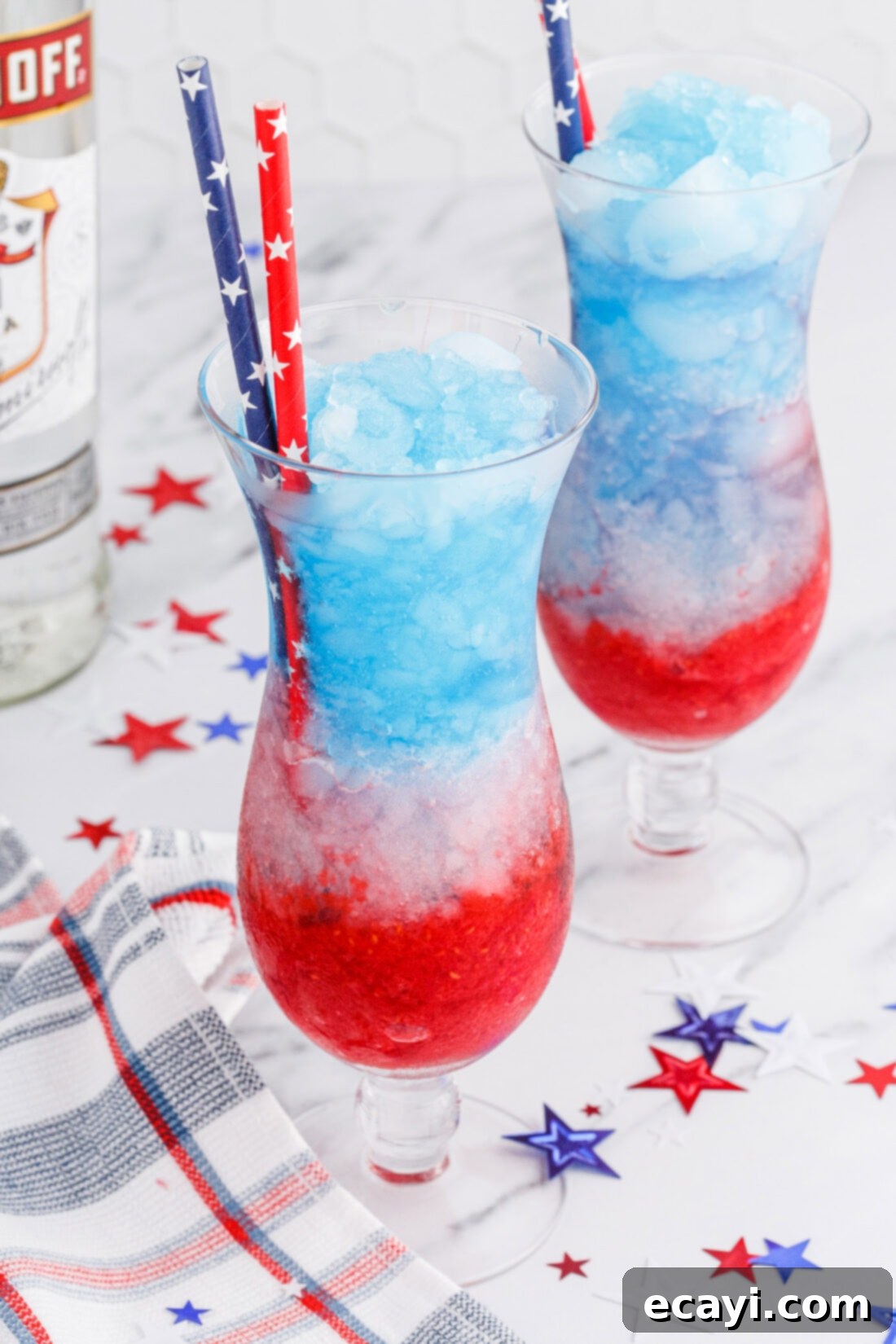 Red White & Boozy Freeze 3 Two vibrant Patriotic Vodka Lemonade Slushies in Poco Grande glasses, adorned with straws and patriotic decorations, ready to be enjoyed at a summer celebration.