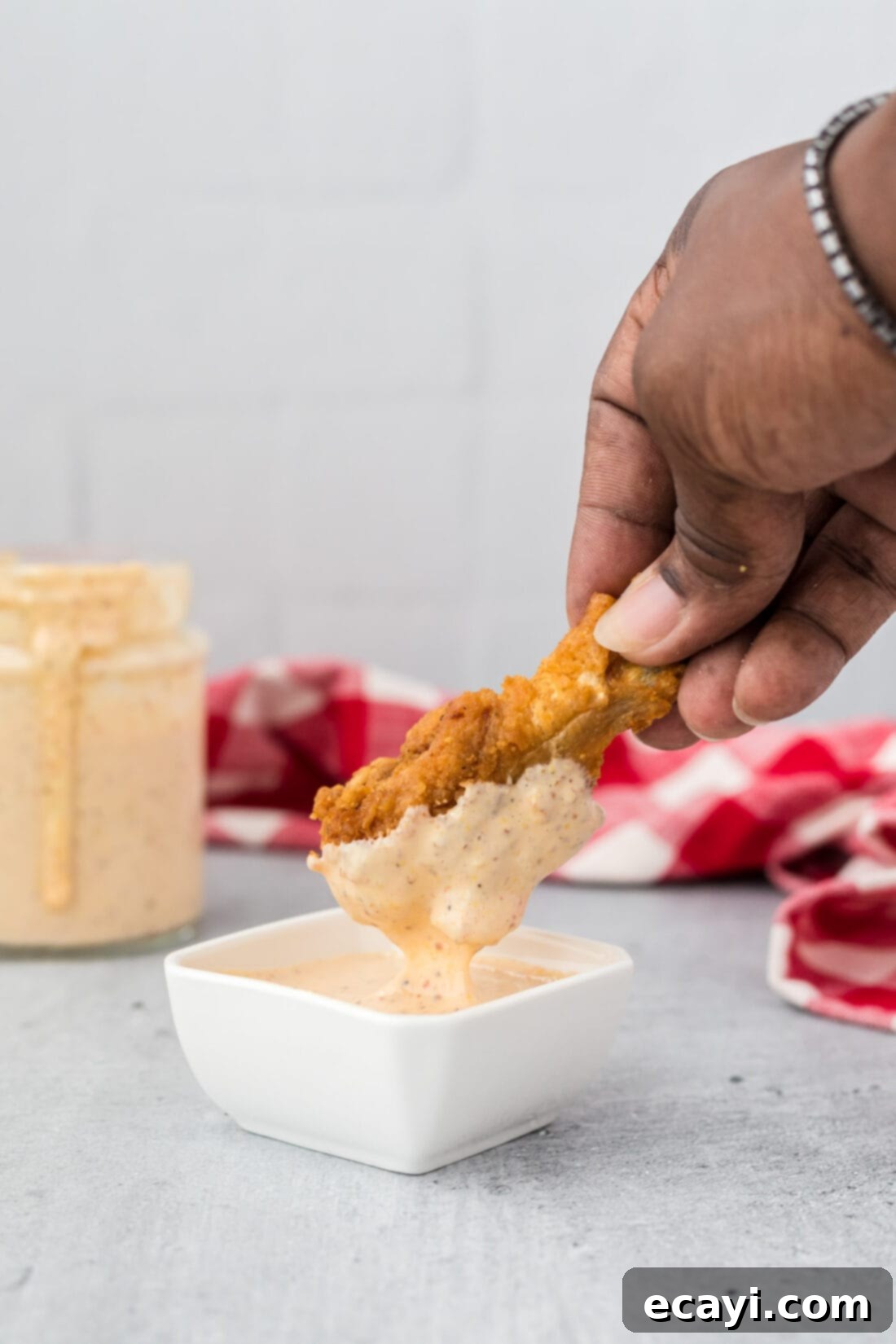 Tangy Southern White BBQ Sauce 3 dipping chicken wing into Alabama White Sauce, illustrating its perfect consistency for dipping